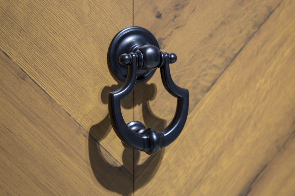 Black door knocker on a wood-effect front door
