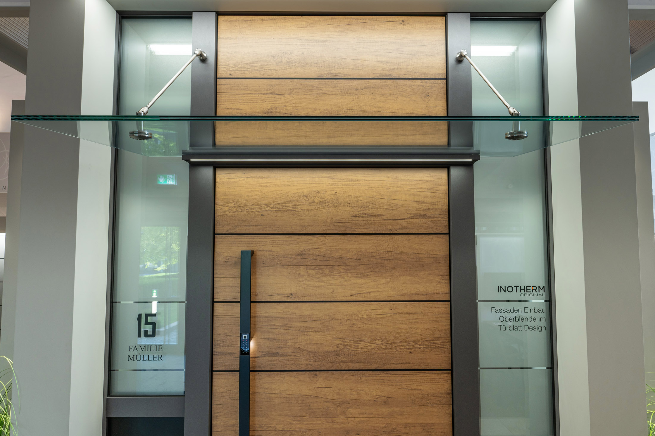 A modern house entrance featuring a sleek black front door with glass panels, surrounded by a minimalist facade with warm lighting.
