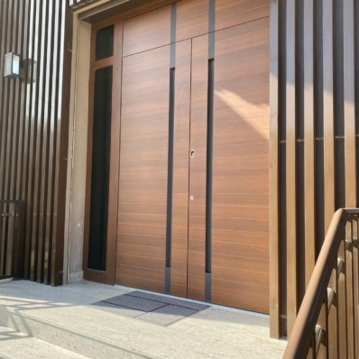 Dvokrilna vrata v lesnem dekorju in polnilom nad vrati ter motivom, ki optično podaljša poglobljena ročaja