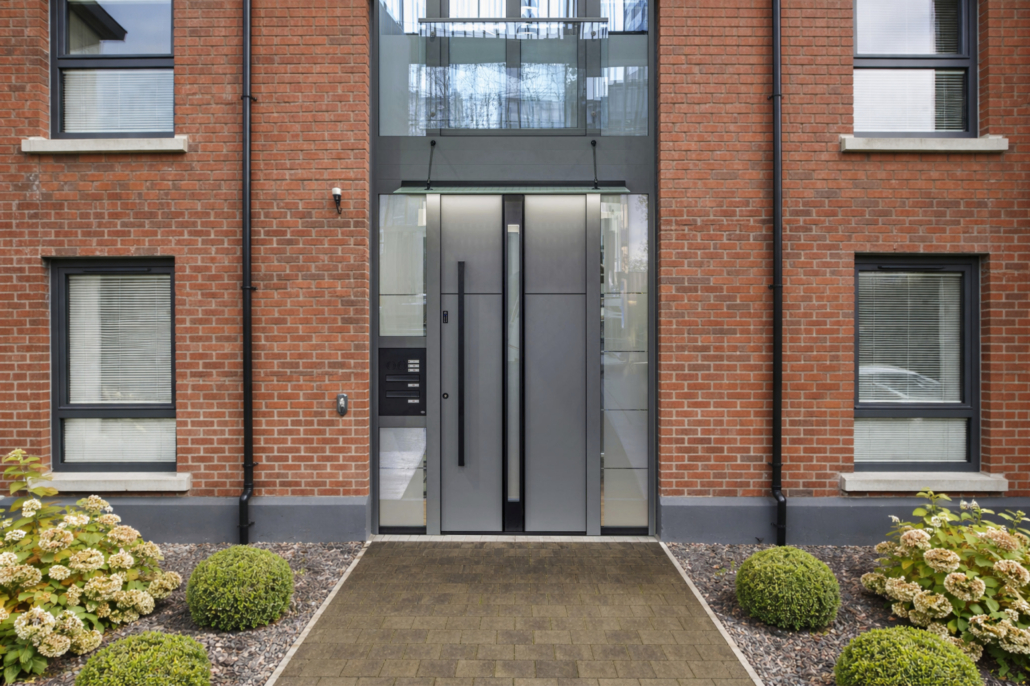 Grey entrance door with a letterbox on a red brick apartment building façade
