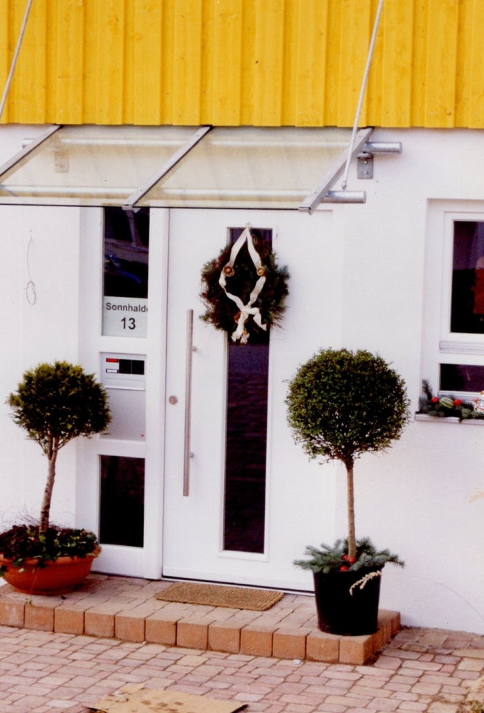 Old image of a white door with glass, a letterbox and a canopy